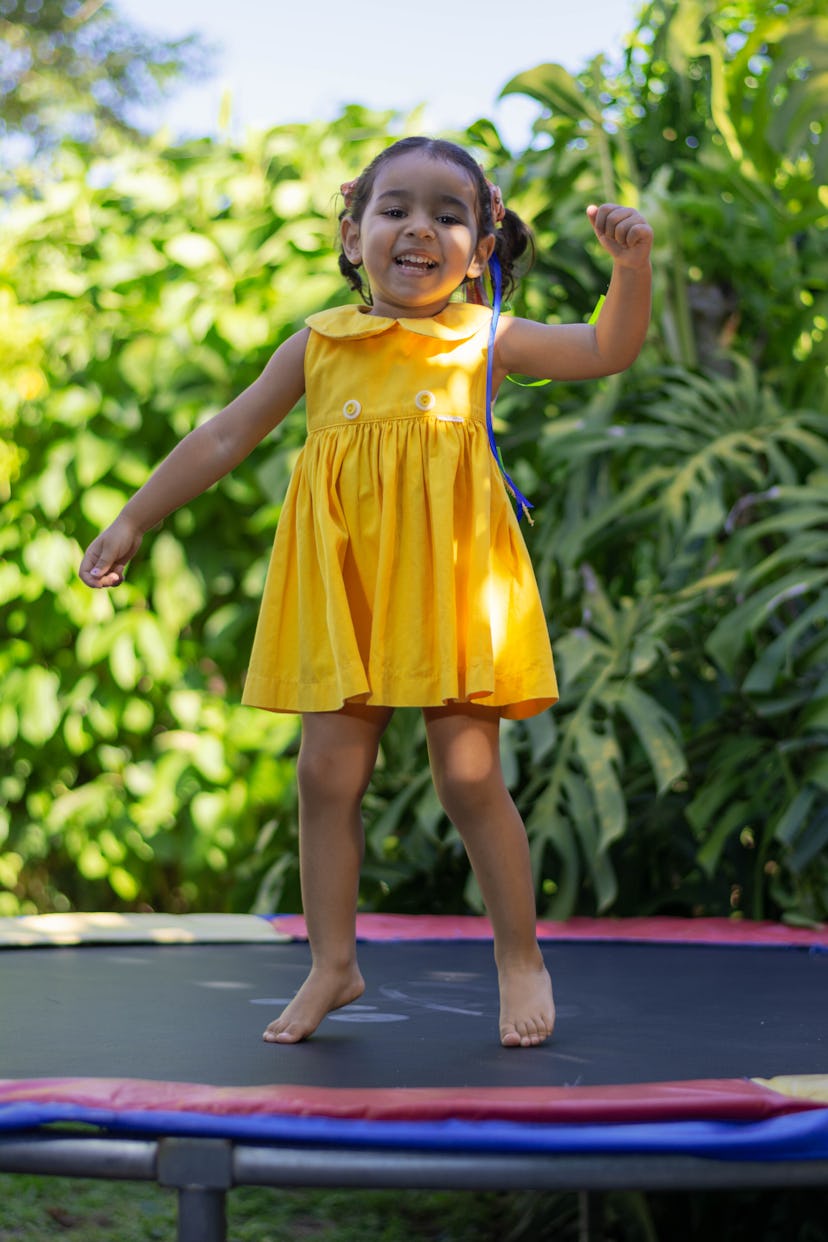 happy little girl playing in the yard in her yellow dress.