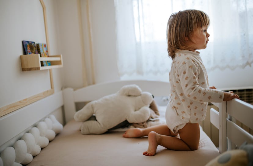 Cute little girl standing on her bed