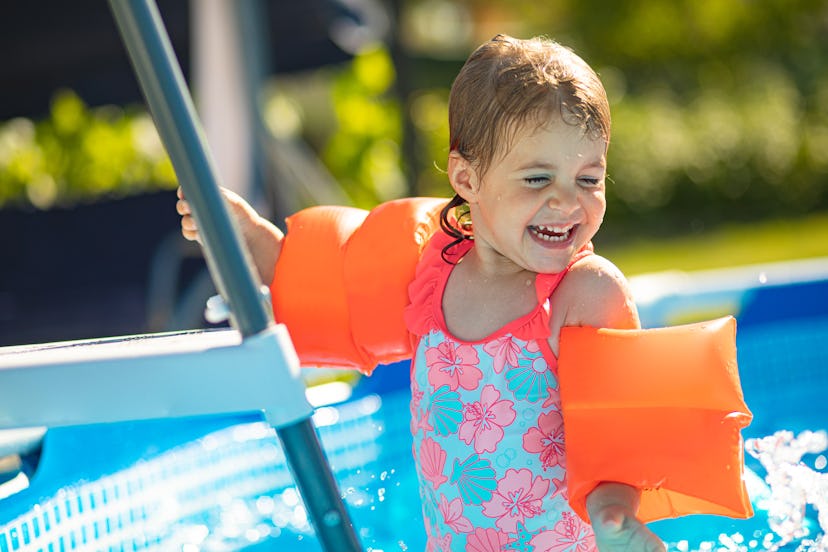  toddler girl standing on swimming pool ladder