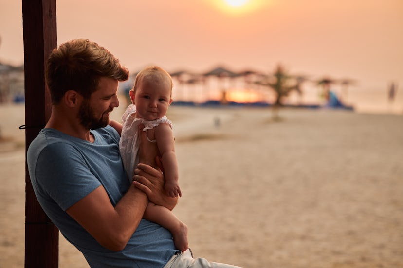 Young father and baby enjoying a tropical paradise beach during sunset.