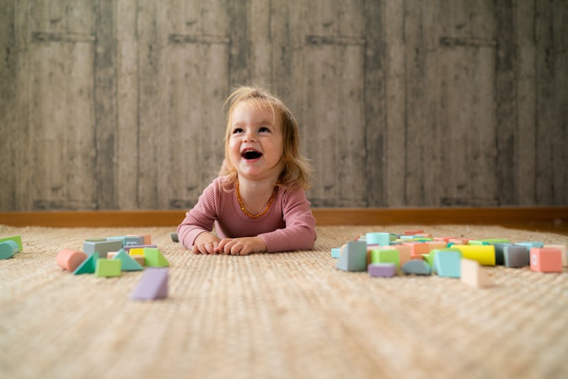 little girl smiling while lying on the floor at home