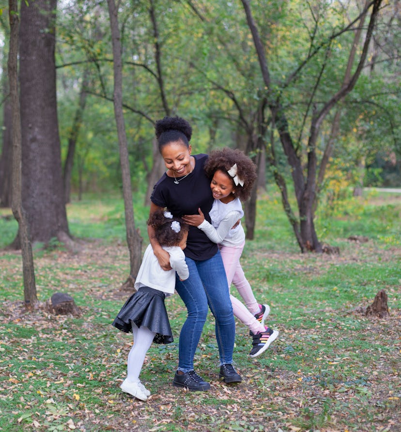 mother and her daughters hug in park