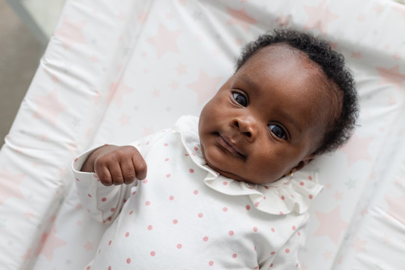 Newborn baby girl laying on a changing mat looking up at the camera