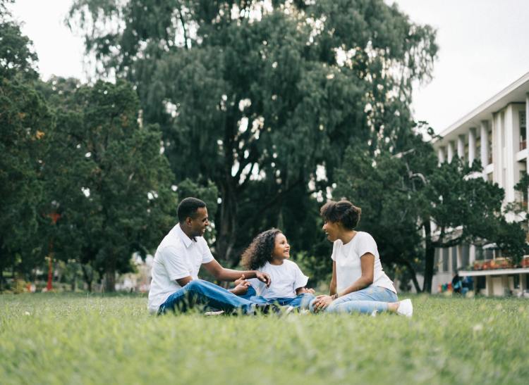 family sitting on grass near building