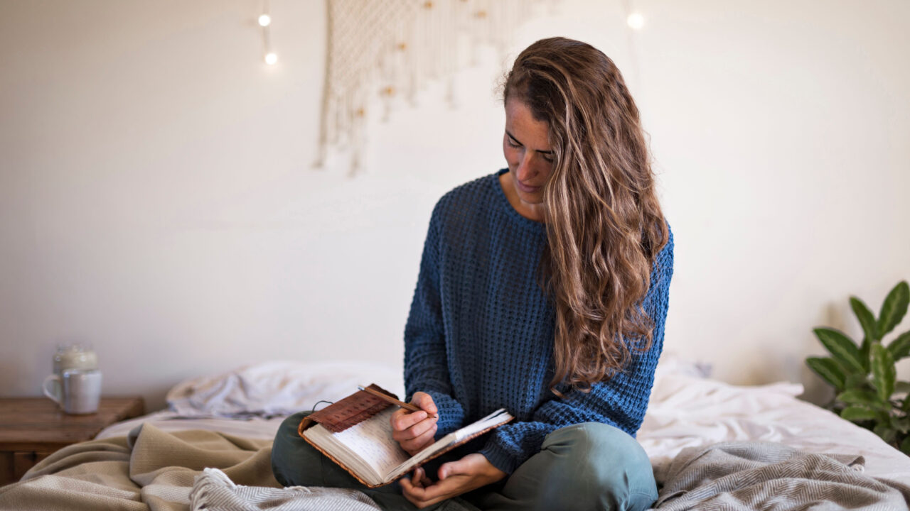 Woman journaling in bedroom.