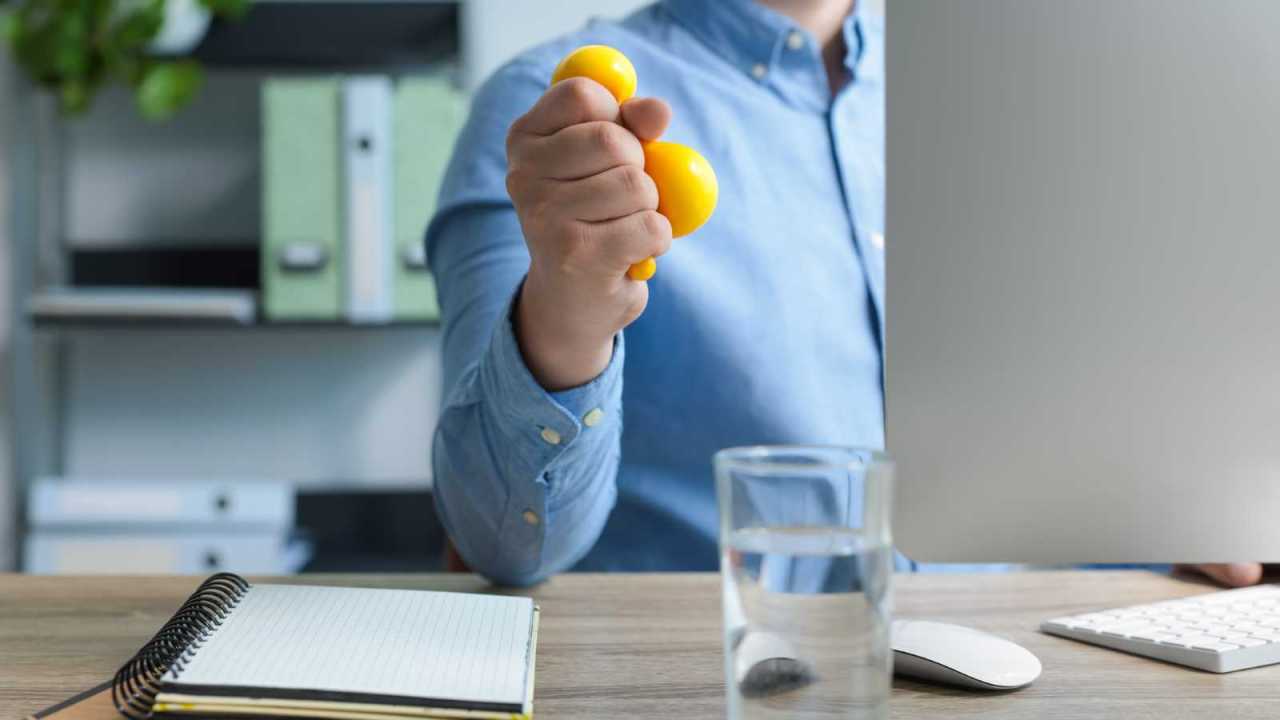 Man playing with stress ball while working at computer.