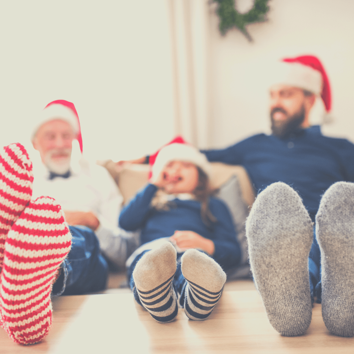 A grandfather, child, and father sitting on a sofa wearing Santa hats and playing Would You Rather Christmas.