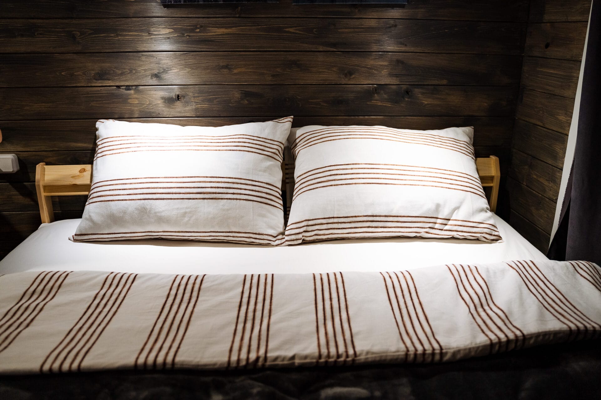 Paired pillows made of soft fabric with a geometric pattern. Cozy wooden room,Deep sleep. The dim light in the wood room. Cotton bed linen. High quality photo