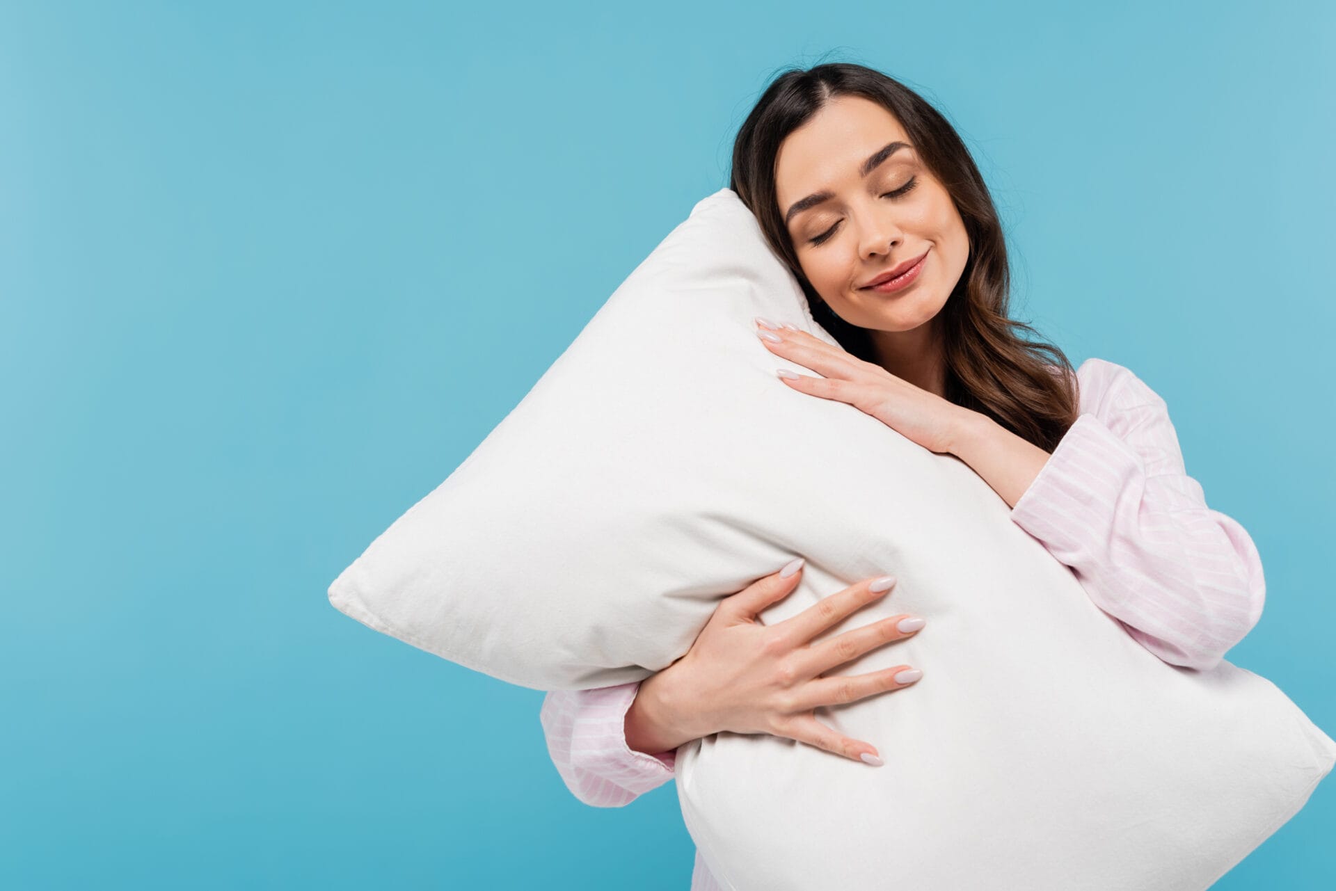 Woman holding white organic pillow with blue background