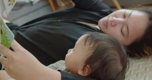 mother reading to infant in bed, quiet and calm time together