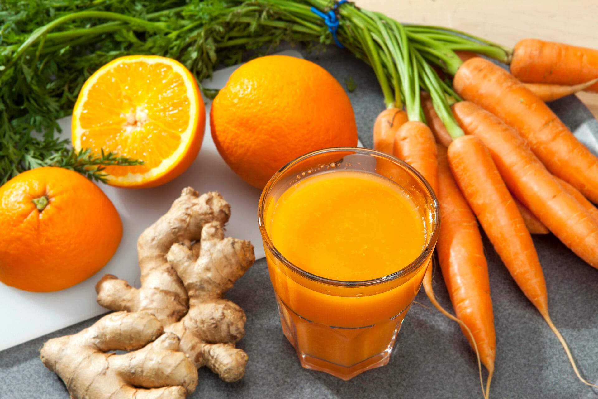 carrots with carrot juice next to an orange on a table