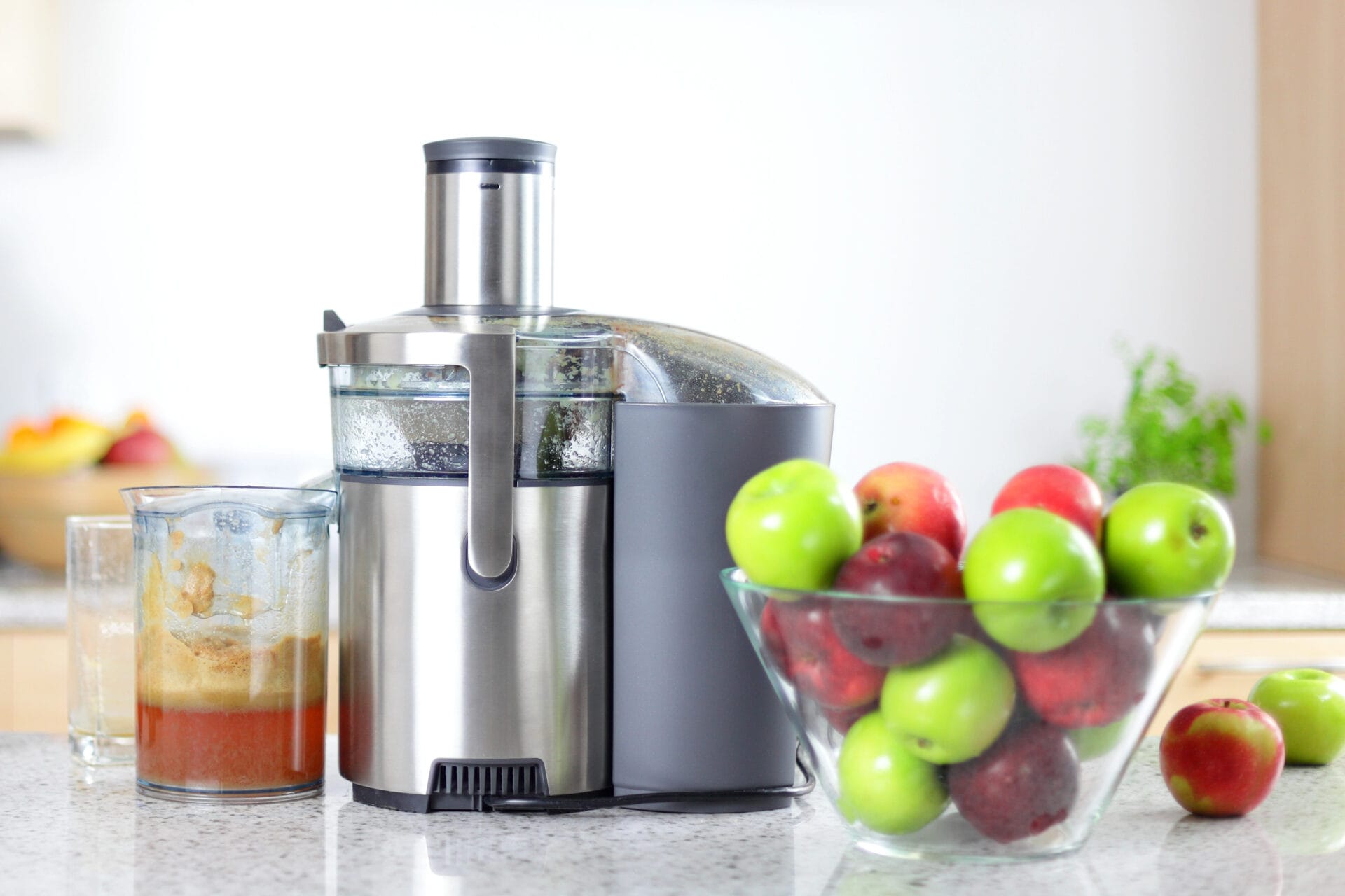 Non-toxic juicer on table with glass bowl of apples