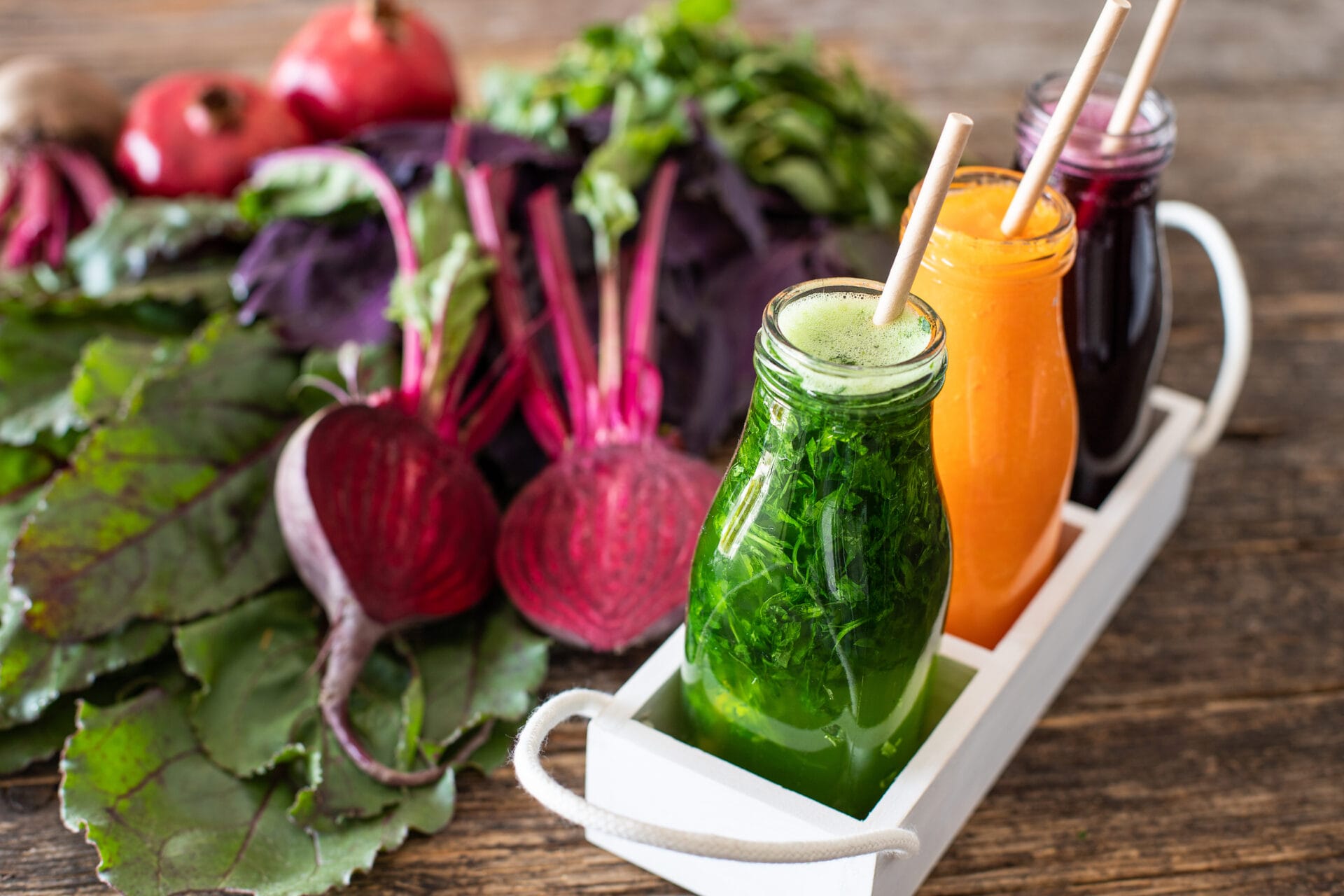 Beet juices and other types of juices on a platter on a hardwood table