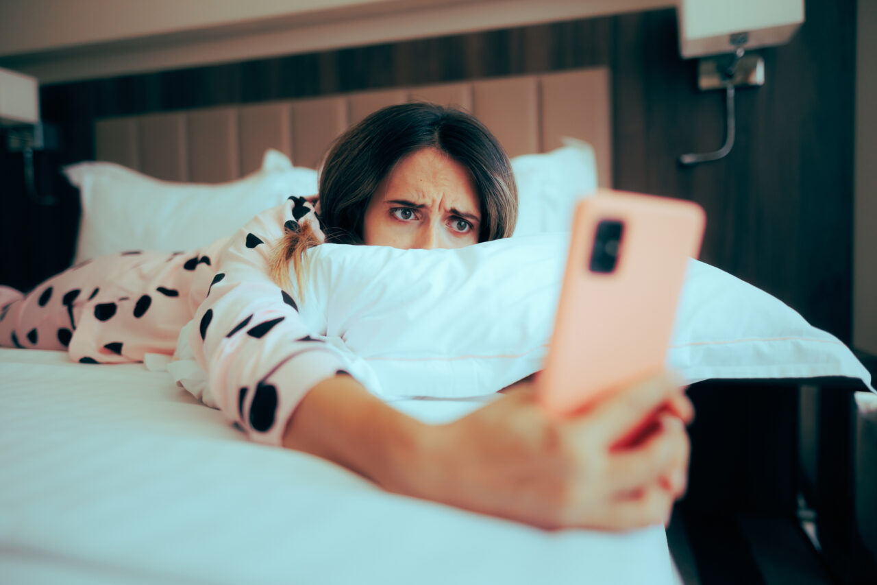 Worried Woman Looking at her phone Lying in Bed