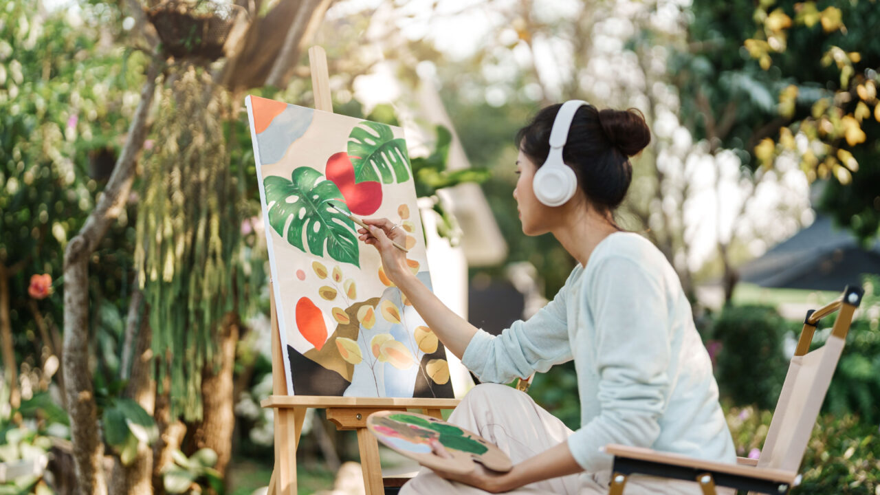 Calm woman painting while listening to music outside.