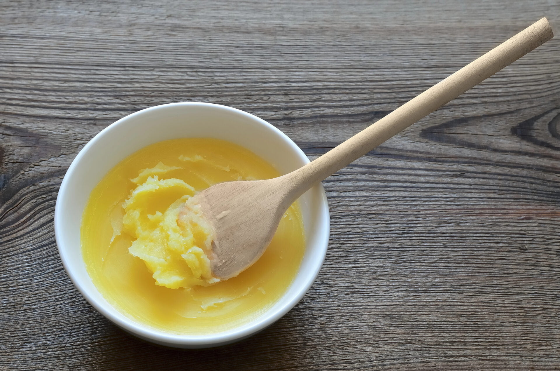 ghee in ceramic pot with wooden spoon