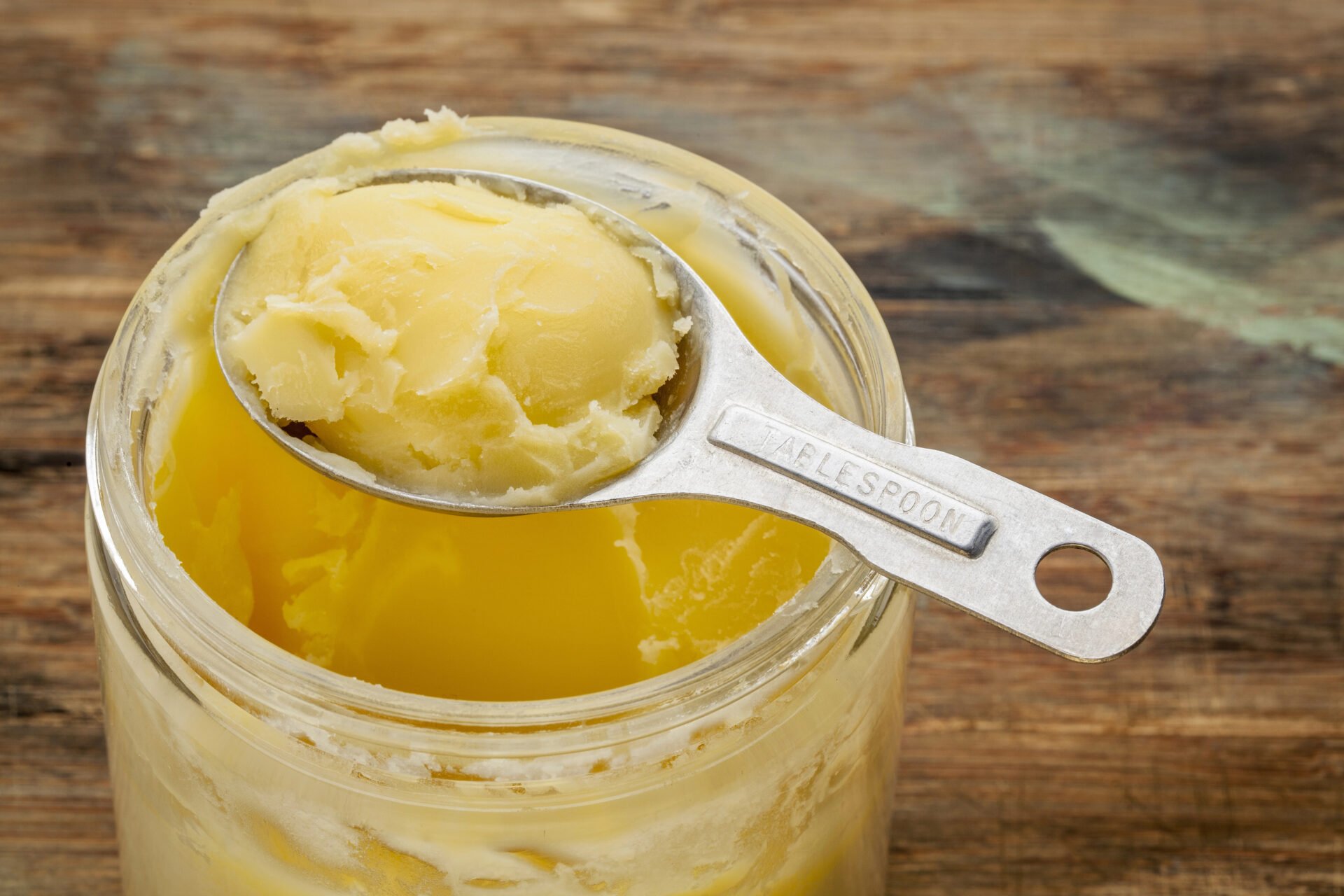 ghee in a glass jar with stainless steel spoon tablespoon