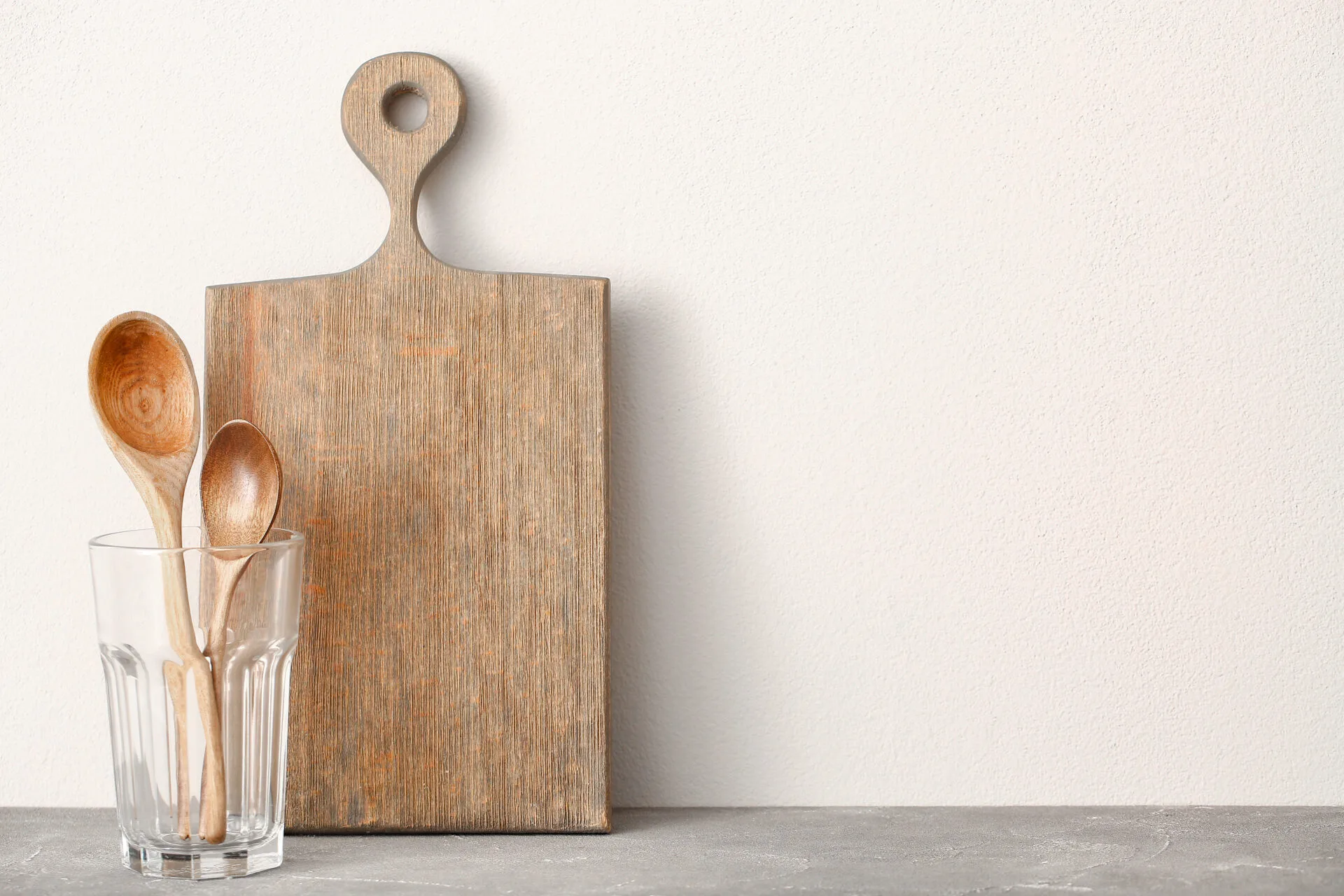 Kitchen utensils on grey table near white wall