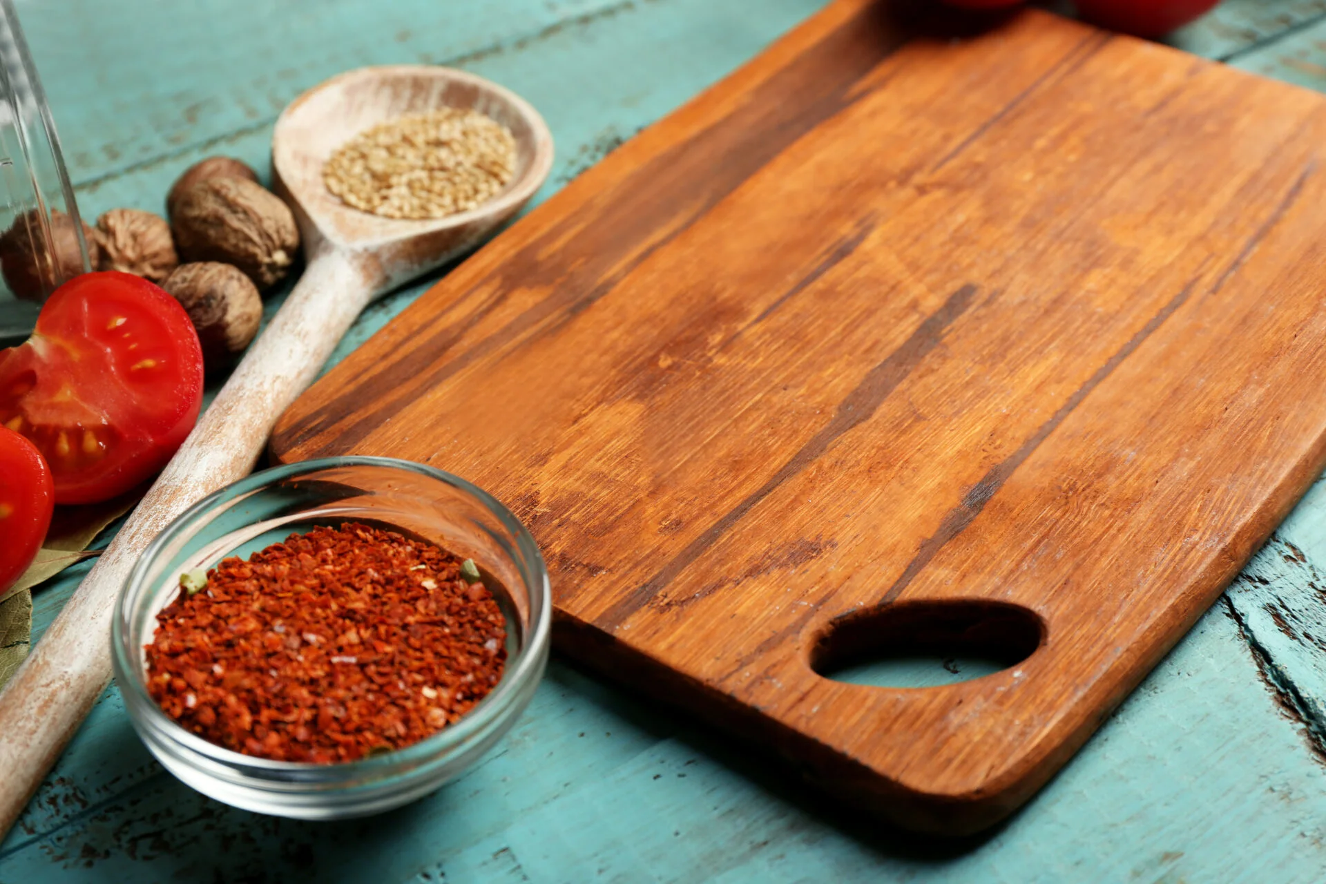 Different spices and herbs with cutting board on color wooden table background