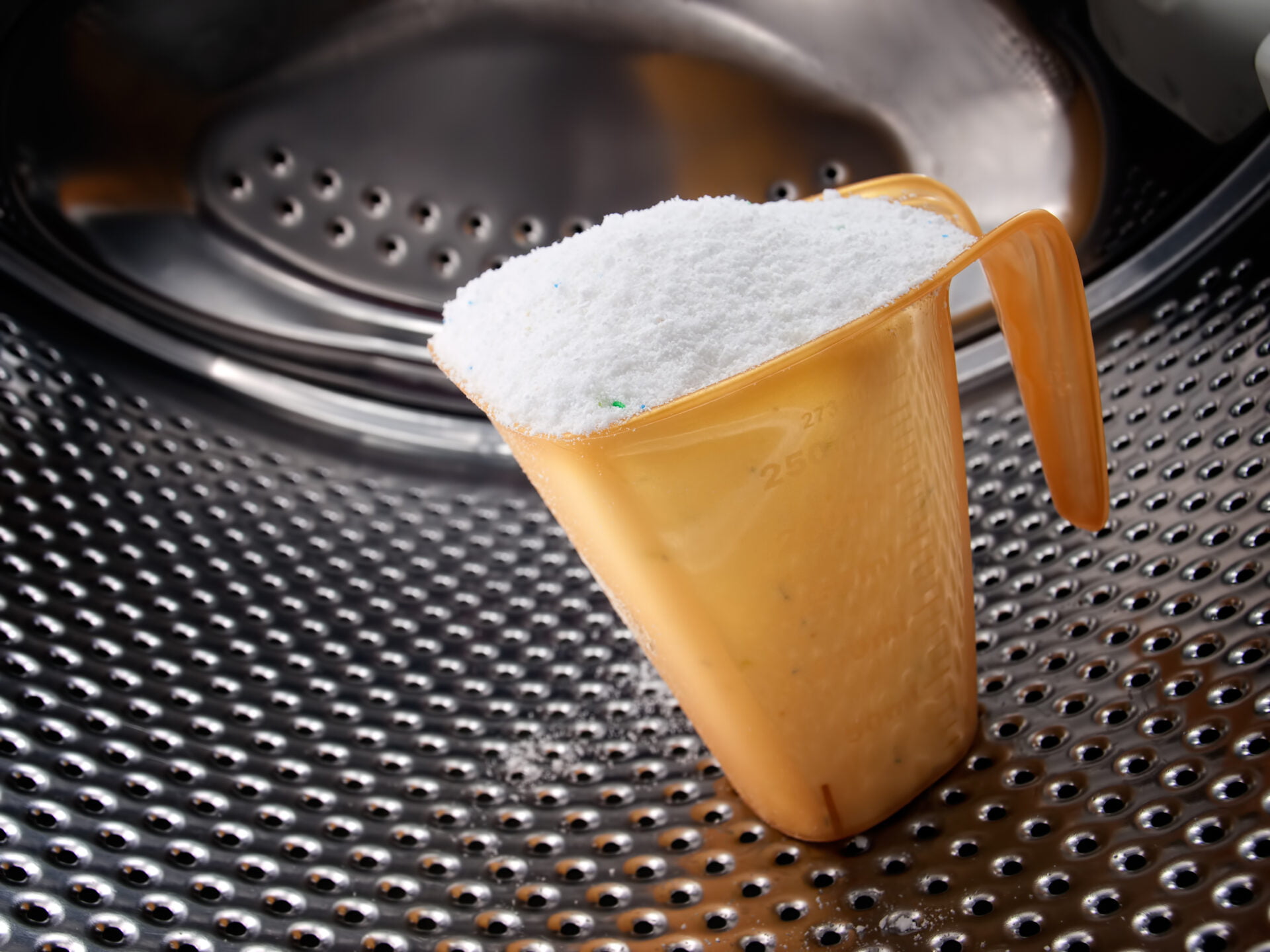 Measuring cup full of detergent in the washing machine