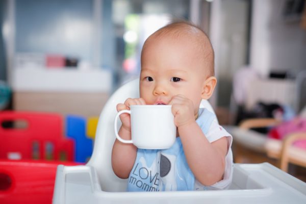 Baby drinking from glass mug