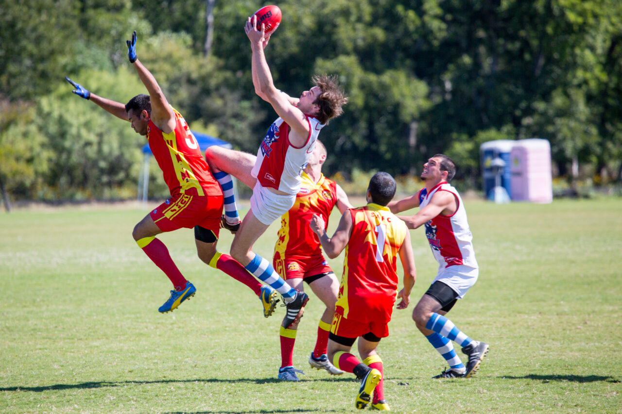 Men in bright uniforms with a ball in the air all trying to catch it.