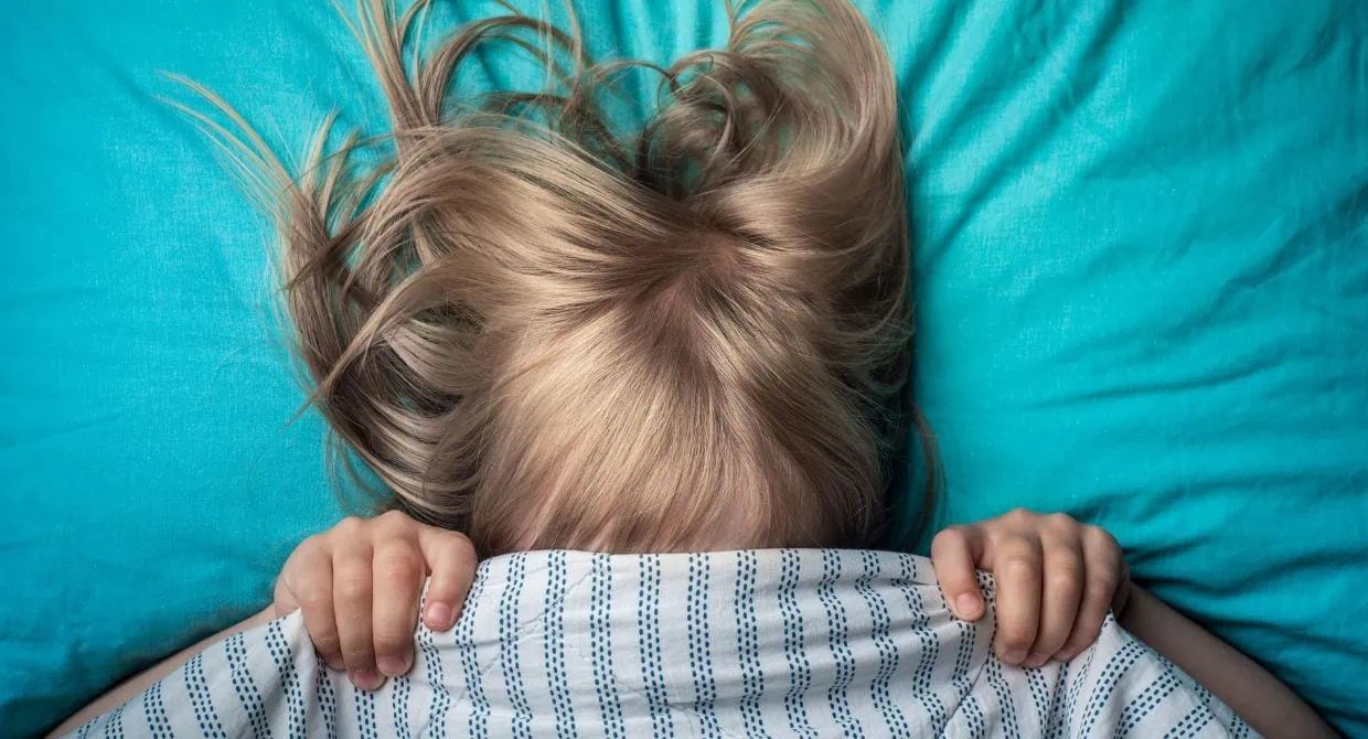 girl hiding under covers