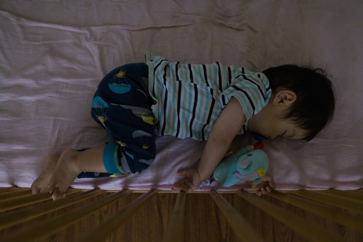 baby curled up asleep in crib