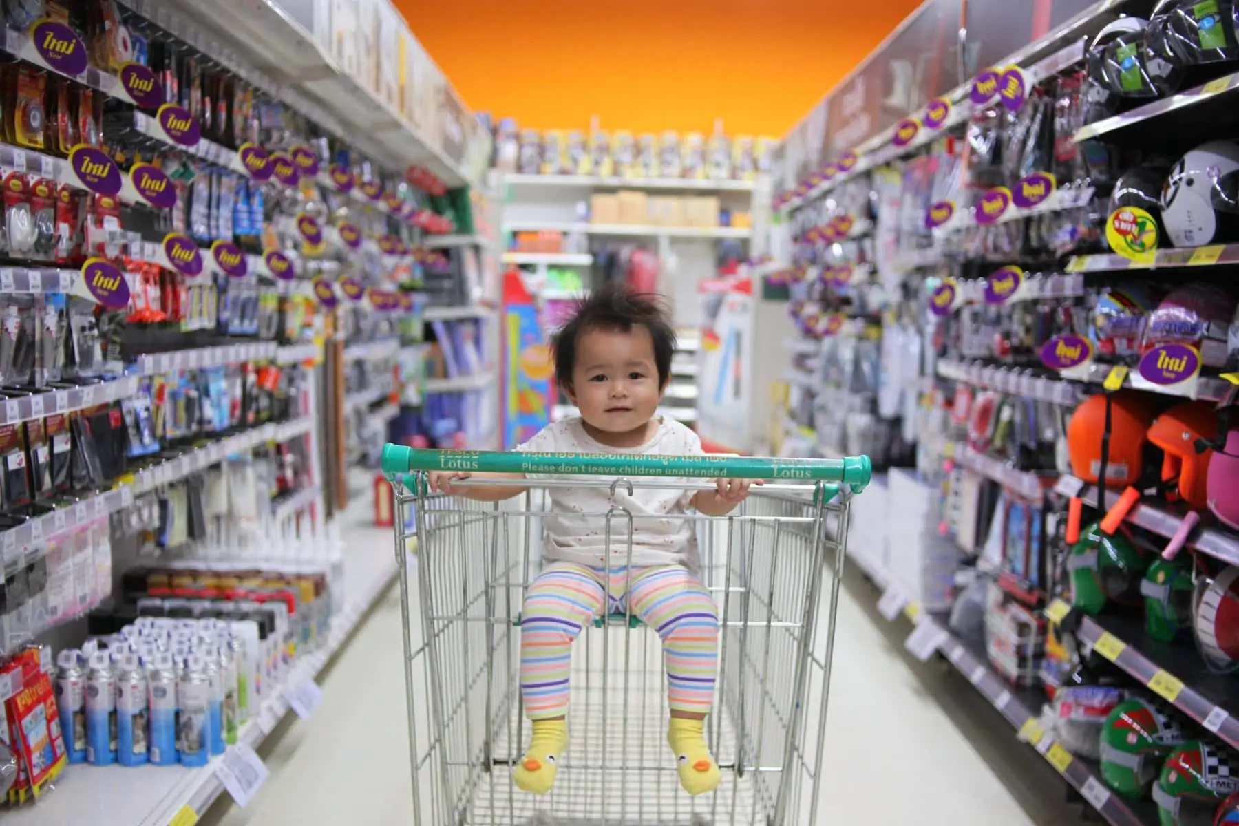 kid in shopping cart in shopping aisle