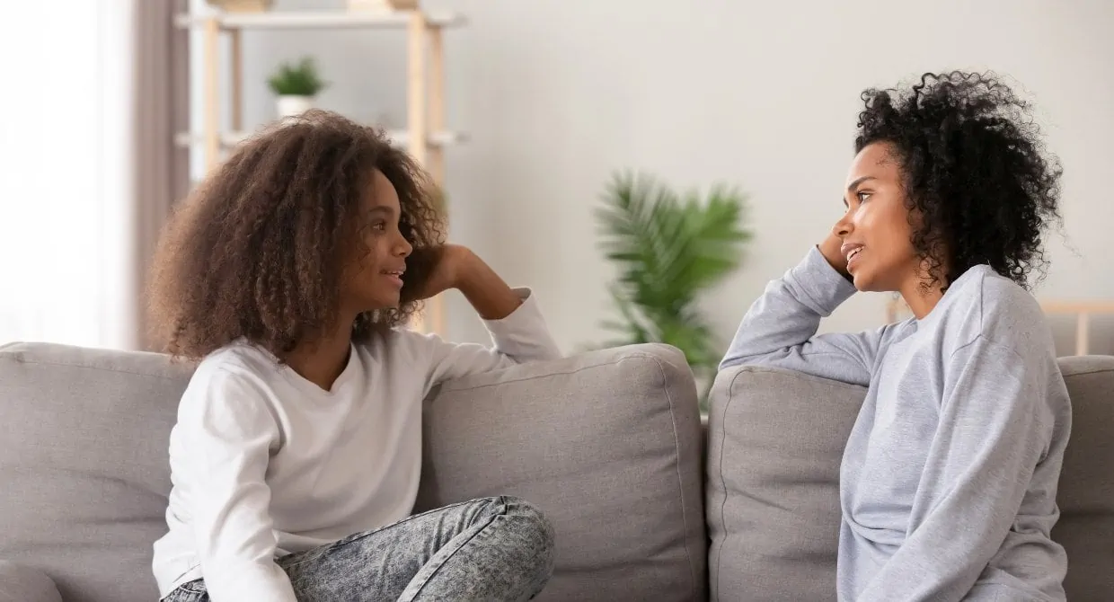 woman and girl sitting on couch talking